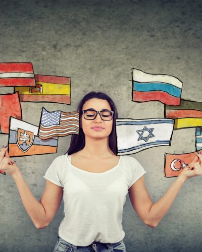 Young girl meditating learning different languages being exposed to different cultures by man and woman with opened boxes and international flags flying away